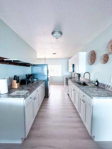 a large kitchen with white cabinets and a blue wall at Sebastian Saltwater Lodge in Sebastian