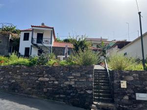a stone retaining wall with a stone stairway in front of a house at Casa do Avô in Ponta do Sol