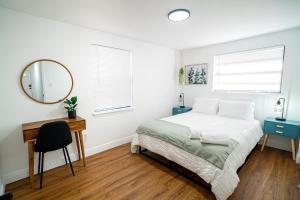 1 dormitorio con cama, escritorio y espejo en Casita-stylish Garden Home 5 Min To Bayshore Water, en Tampa