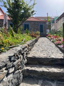 um caminho de pedra em frente a uma casa com flores em Casa do Avô em Ponta do Sol