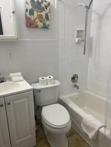 y baño blanco con aseo y bañera. en Marvelous 3BR in NYC! en Nueva York