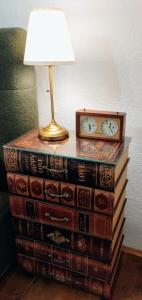 eine Lampe auf einem Stapel Bücher mit einer Uhr oben in der Unterkunft Honey house Lika in Gospić