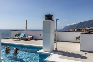 a swimming pool with two people in the water at EDEN RENTALS Seaside Getaway in Puerto de Santiago