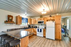 a kitchen with wooden cabinets and a white refrigerator at Serene Belgrade Hideaway with Fire Pit and Grill! 