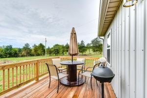 a deck with a table and chairs and an umbrella at Serene Belgrade Hideaway with Fire Pit and Grill! 