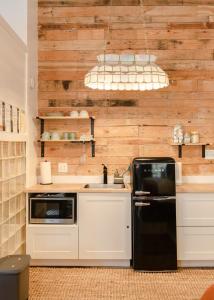 uma cozinha com um frigorífico preto e uma parede de madeira em 1885 Garden Studio - Historic Heart of Savannah - Pulaski Ward em Savannah
