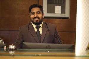 a man in a suit sitting at a table with a laptop at THE K HOTEL in Dubai