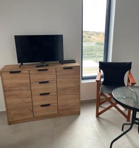 a television on a dresser with a table and a chair at Souvala /Aegina. Excellent location Luxury villa. in Vathí