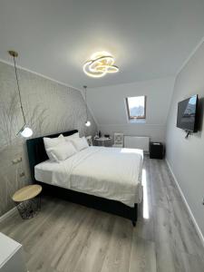a bedroom with a large white bed and a tv at Glam Studios in Sibiu