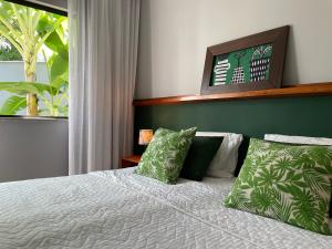 a bedroom with a bed with green and white pillows at Chalé Litoral Norte - em condomínio de praia in Camaçari +41 photos