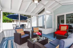 eine abgeschirmte Veranda mit Stühlen und einem Sonnenschirm in der Unterkunft Quaint Cottage in a South Sarasota Neighborhood in Sarasota