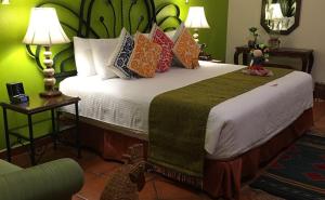 a bedroom with a large bed with colorful pillows at Hotel Boutique Parador San Miguel Oaxaca in Oaxaca City
