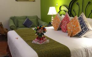 a doll sitting on top of a bed with pillows at Hotel Boutique Parador San Miguel Oaxaca in Oaxaca City