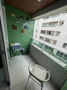 Un balcón con una silla y una ventana y una mesa. en Apto 200m mar de Cabo Branco, en João Pessoa