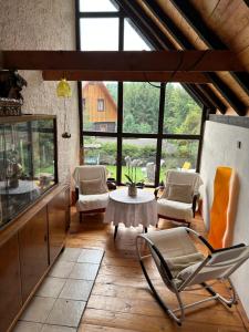 - un salon avec une table, des chaises et des fenêtres dans l'établissement U Suchánků, à Jetřichovice