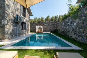una piscina en un patio junto a una pared de piedra en IZZ Getaway - Adults Only, en Göcek
