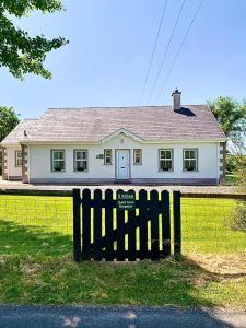 a white house with a black fence in front of it at Quiet Farm Bungalow Enniskillen Fermanagh in Enniskillen