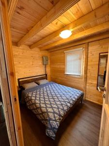 ein Schlafzimmer mit einem Bett in einer Holzhütte in der Unterkunft The Pines Cottage On The Lake in Otter Lake