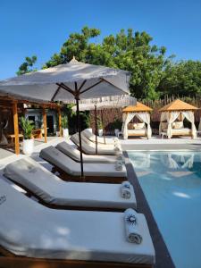 un grupo de tumbonas y una sombrilla junto a la piscina en Bora Bora Beach Club & Hotel, en Isla Grande