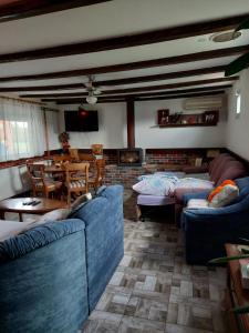 a living room with blue couches and a dining room at Home of nature - kuća prirode in Odžak