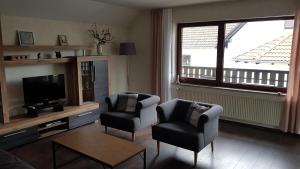 een woonkamer met 2 stoelen en een flatscreen-tv bij Haus Weinheck in Lebach