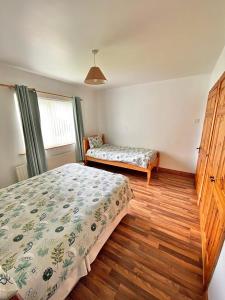 a bedroom with two beds and a wooden floor at Quiet Farm Bungalow Enniskillen Fermanagh in Enniskillen
