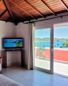 um quarto com uma televisão e uma grande porta de vidro em Mata Hari Apartamentos em Búzios