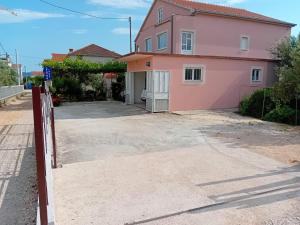 a pink house with a driveway in front of it at Apartman Laura in Kaštela