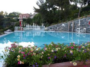 a large swimming pool with blue water and flowers at Excelsior Palace Portofino Coast in Rapallo