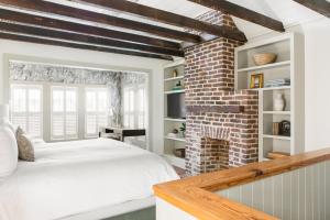 een slaapkamer met een wit bed en een bakstenen muur bij 86 Cannon Historic Inn - Adults Only in Charleston