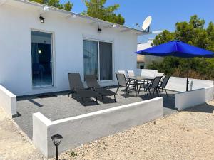 een patio met een tafel en stoelen en een parasol bij Paradis Studios in Archangelos