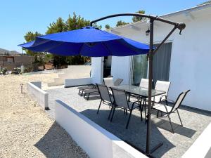 een tafel en stoelen met een blauwe parasol op een patio bij Paradis Studios in Archangelos