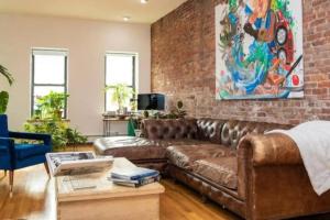 a living room with a brown leather couch and a brick wall at Unique 1BR Greenwich Penthouse Escape! in New York