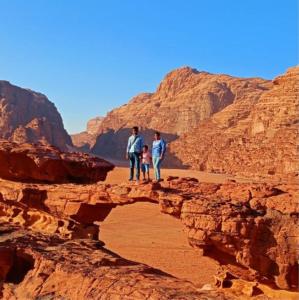 Um homem e duas crianças numa ponte no deserto. em moon city with jeep trips em Wadi Rum