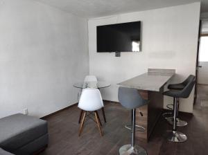 グアダラハラにあるDepartamento cerca de zoológico y estadio Jaliscoのテーブル、椅子、テレビが備わる客室です。