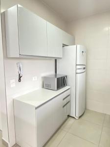 a kitchen with white cabinets and a white refrigerator at TULUM Bertioga - belo apartamento com vista para o mar in Bertioga