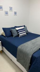 a large bed with blue sheets and pillows on it at TULUM Bertioga - belo apartamento com vista para o mar in Bertioga