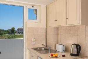 une cuisine avec un évier et une plaque de fruits sur le comptoir dans l'établissement Manousis ApartHotel, à Tsilivi