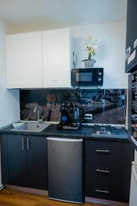 a kitchen with black cabinets and a sink and a microwave at Relaxveld Galaxy in Curtea de Argeş