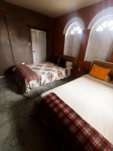 two beds in a room with two windows at HOTEL EL PANECILLO-Tanta in Quito