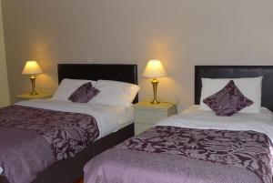 two beds in a hotel room with two lamps at Quay House in Wexford