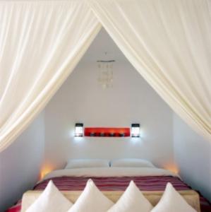 a bedroom with a bed with white curtains and pillows at Dar Lazuli Bed & Breakfast in Essaouira
