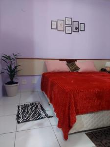 a bedroom with a red bed and a potted plant at Flat Palladium in São Vicente