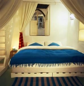 a bedroom with a blue bed with a window at Dar Lazuli Bed & Breakfast in Essaouira +10 photos