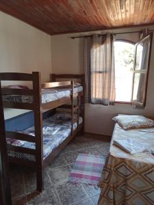 a room with two bunk beds and a window at Pousada Véu de Noiva in São Thomé das Letras