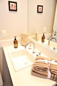a white bathroom with a sink and a mirror at Apartamento 1903 no Bosque com quarto cozinha completa e vaga de garagem in Campinas +54 photos