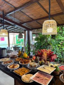 a table with a bunch of food on it at Pousada Le Baron in Praia do Frances