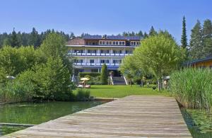 ein großes Gebäude mit einem Holzsteg neben einem See in der Unterkunft Strandhotel Klopeinersee in Sankt Kanzian am Klopeiner See