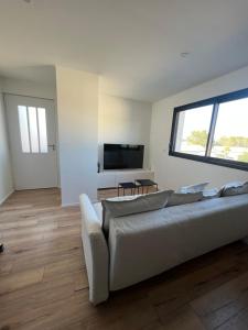 un salon avec un canapé blanc et une télévision dans l'établissement Joli appartement neuf avec jardinet, à Roquebrune-sur Argens