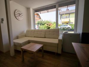 a living room with a couch and a clock on the wall at Sport apartments in Radovljica
